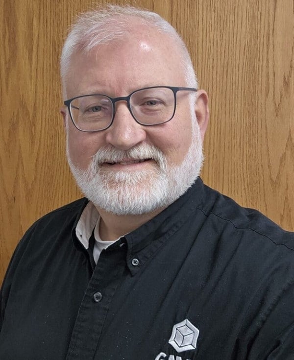 A photograph of John Stacy, a man with short cut white hair and a short white beard.